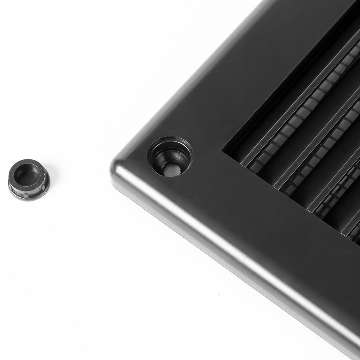 Close-up of Awenta black air vent grille corner showing screw hole and cover cap.