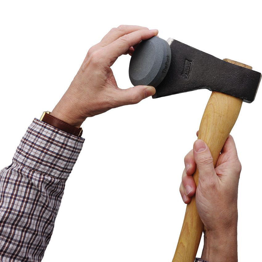 Person using Lansky The Puck dual grit stone to sharpen an axe blade.